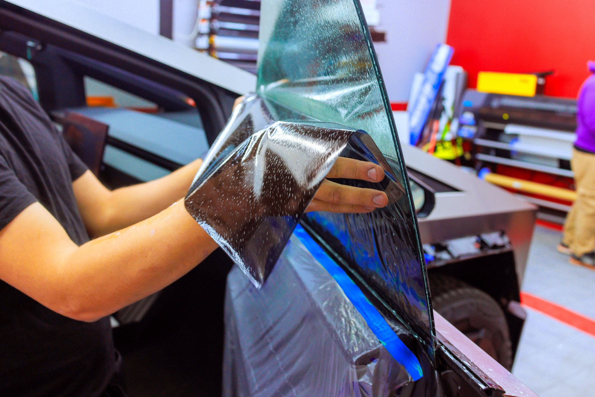 Professional window tint installation in an automotive workshop during daylight hours